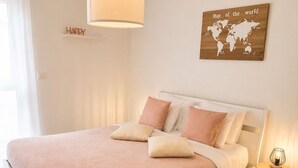 A bedroom with a bed, a bedside table, a lamp, a world map, and a 'HAPPY' sign on the wall. - Calm and Modern apartment (Habscht)