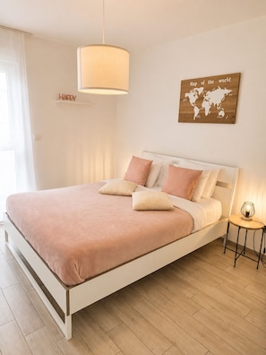 Ett sovrum med en säng, ett sängbord, en lampa, en världskarta och en skylt med texten ”GLAD” på väggen.