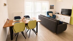 A modern living room with a dining area, a sofa, a TV, and a window with sheer curtains. - Calm and Modern apartment (Habscht)