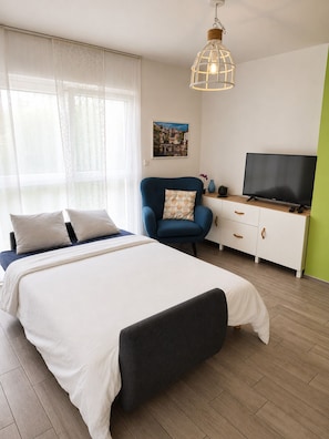 Une chambre à coucher avec un lit, une chaise, un téléviseur et un tableau accroché au mur.