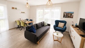 A modern living room with a sofa, armchair, dining table, and a television. - Calm and Modern apartment (Habscht)