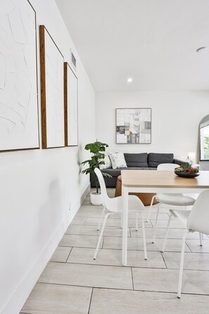 A modern interior with a dining area, white walls, and a grey sofa.