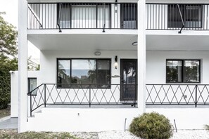 Un immeuble de deux étages doté d’un balcon, d’une porte avec un numéro et d’une fenêtre.