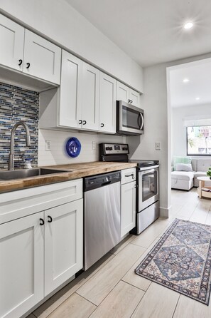 Une cuisine moderne avec des meubles blancs, un four à micro-ondes, un lave-vaisselle et une cuisinière.