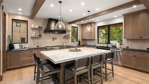 Une cuisine moderne dotée d’un grand îlot central, de meubles en bois et de luminaires suspendus.