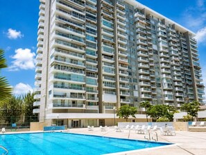 Un hotel moderno con piscina y mobiliario exterior.