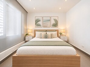 Un dormitorio moderno con una cama grande, mesitas de noche y una ventana.