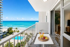 Un balcón con una mesa para dos, con vista a la playa y al océano.