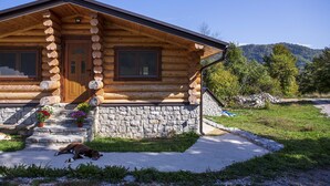 A log cabin with a stone foundation, wooden exterior, and a front porch with steps.