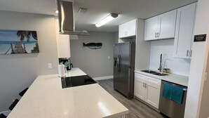 Une cuisine moderne avec des meubles blancs, des appareils en acier inoxydable et un plan de travail noir.