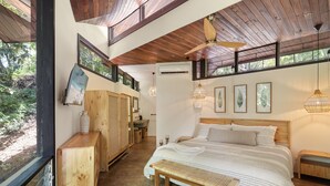 A bedroom with a large bed, wooden ceiling, and a view of greenery outside. - Treehouse Hideaway in Tamarindo Jungle with Pool & Open-Air Living Room (Tamarindo)