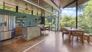 A modern kitchen with a large island, stainless steel appliances, and a view of lush greenery. - Treehouse Hideaway in Tamarindo Jungle with Pool & Open-Air Living Room (Tamarindo)