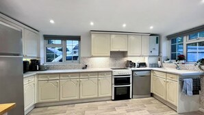A modern kitchen with light-colored cabinetry, a herringbone-patterned floor, and built-in appliances.