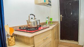 A compact kitchen with a gas stove, a sink, and wooden cabinets. - Aji  Unique 1BED Studio  (Ijegun, Lagos) (Lagos)