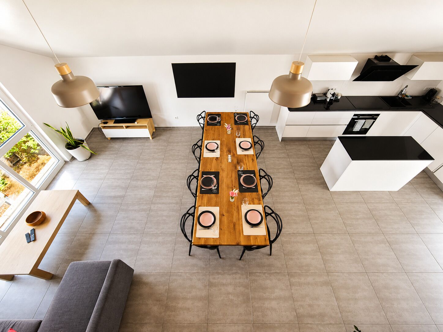 Une cuisine moderne dotée d’un îlot central, d’une table à manger avec des chaises, et d’un canapé dans un espace de vie agrémenté d’une grande fenêtre.