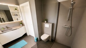 Une salle de bain moderne équipée d’une douche, de toilettes et d’un lavabo.