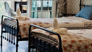 Ein Schlafzimmer mit zwei Betten, jeweils mit floralem Bettbezug und einem schwarzen Metallgestell.