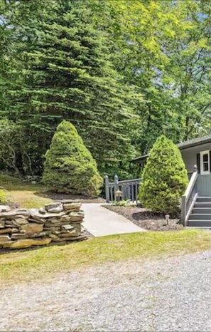 A residential property with a stone wall, a pathway leading to a house, and a well-maintained lawn.