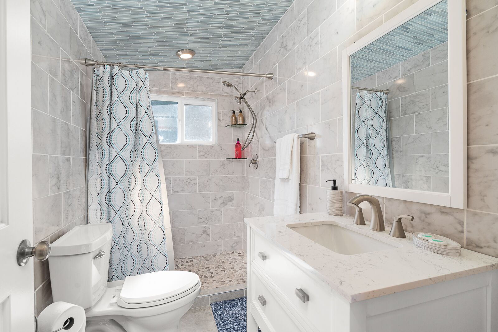 A modern bathroom with a shower, toilet, sink, and mirror.