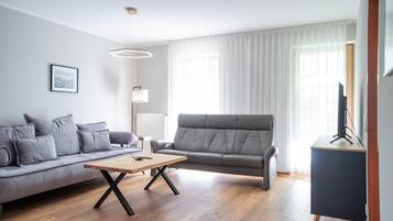 Un salon moderne avec un canapé gris, une table basse en bois et un meuble pour la télévision.