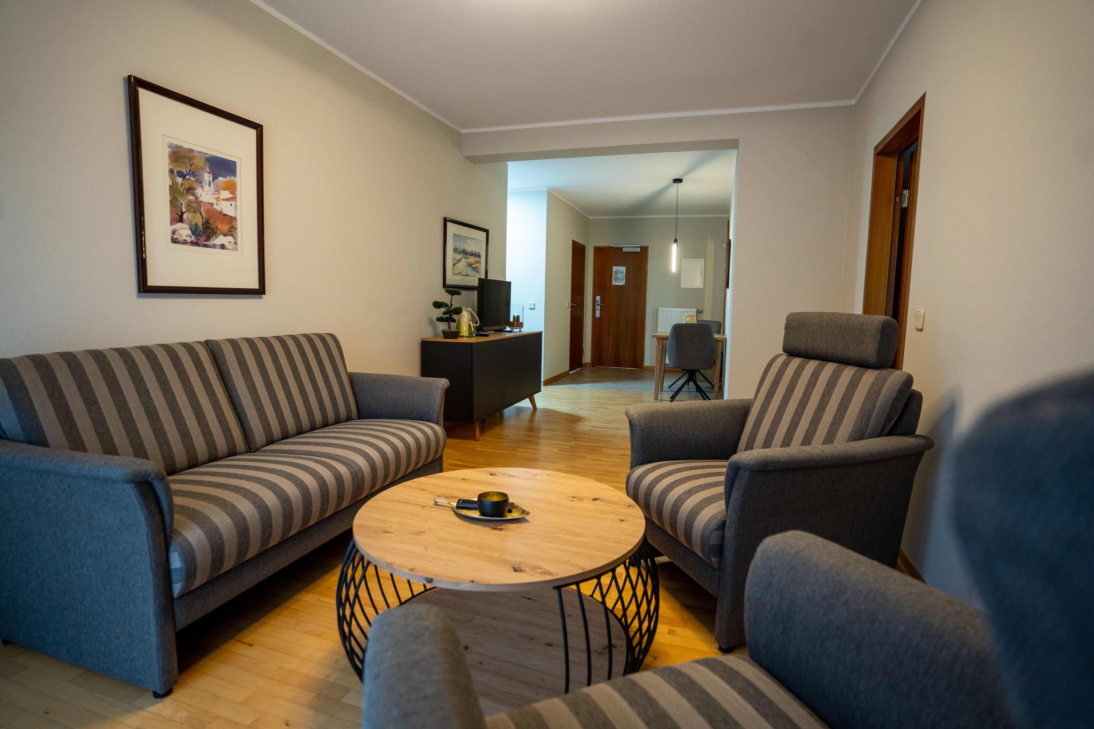 A living room with a sofa, armchairs, a coffee table, and a television on a stand.