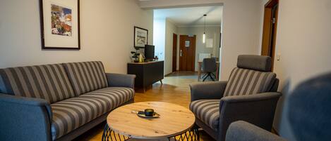 A living room with a sofa, armchairs, a coffee table, and a television on a stand.