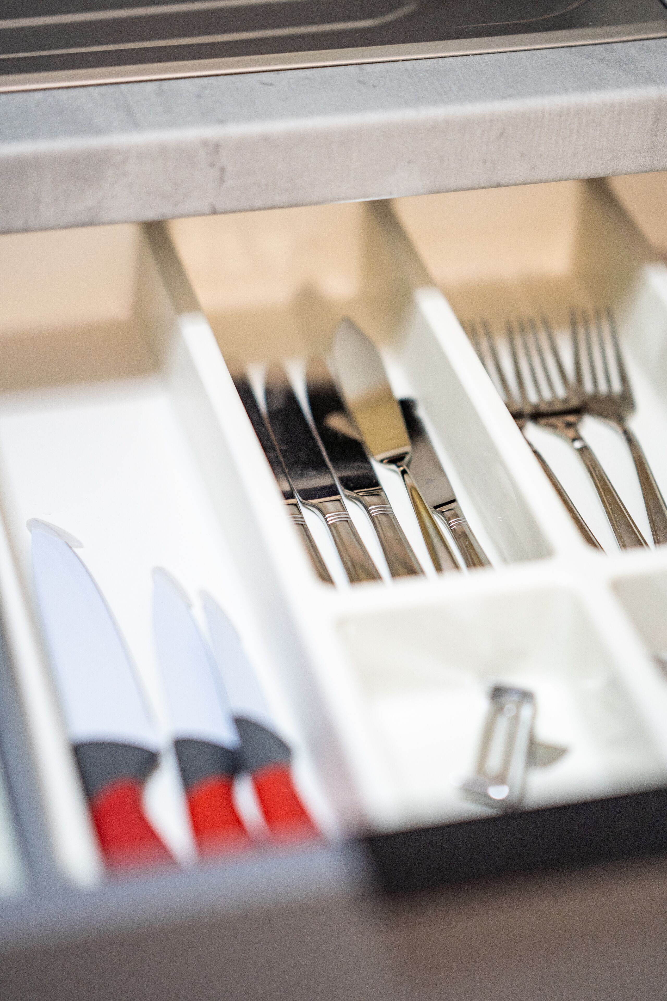 A drawer containing various utensils including knives, forks, and spoons.