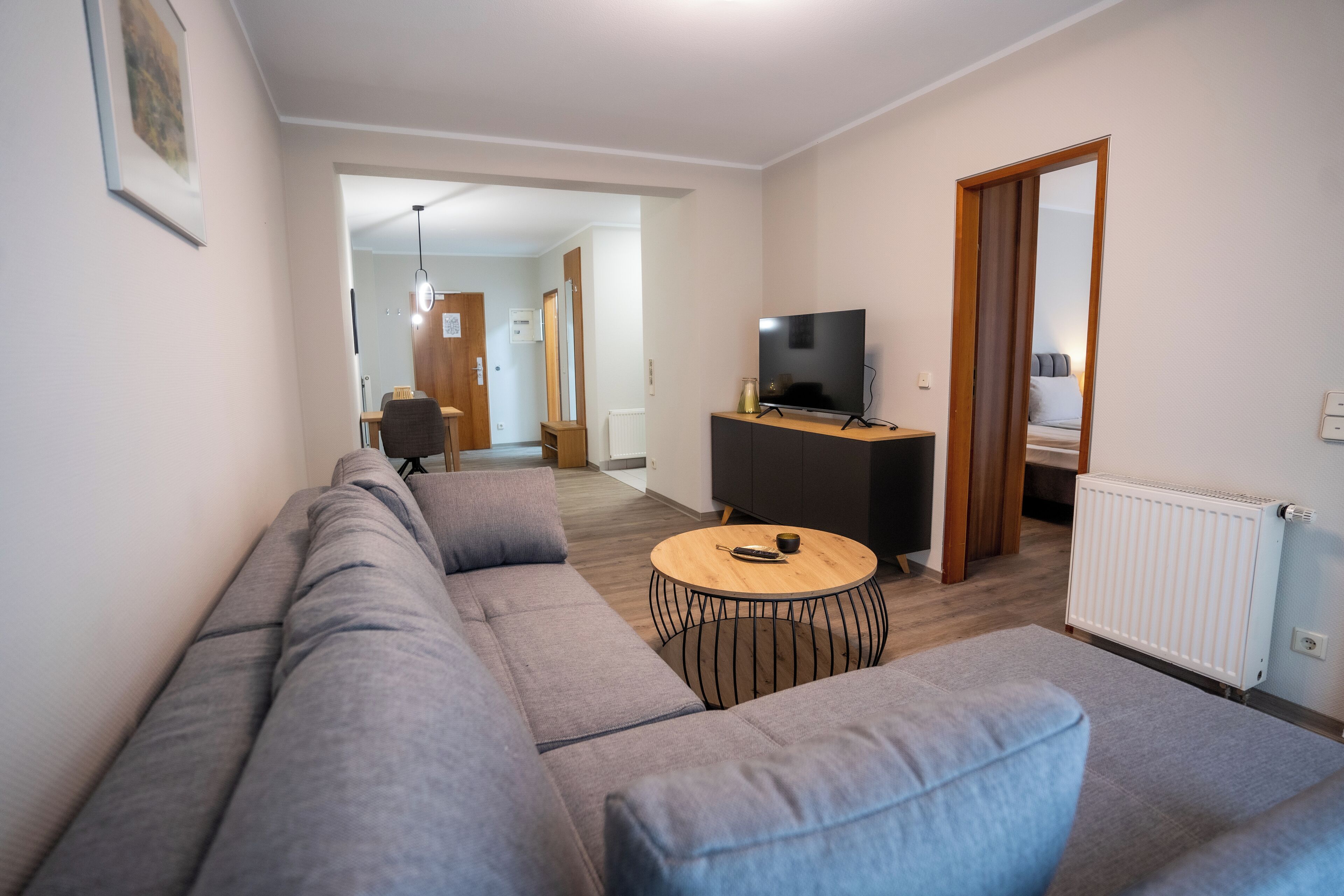 Una sala de estar moderna con un sofá gris, una mesa de centro y un televisor sobre un mueble.