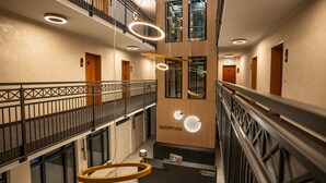 Un espace d’accueil d’hôtel au design moderne, comprenant un comptoir d’accueil, un escalier et une vue sur le hall d’entrée.