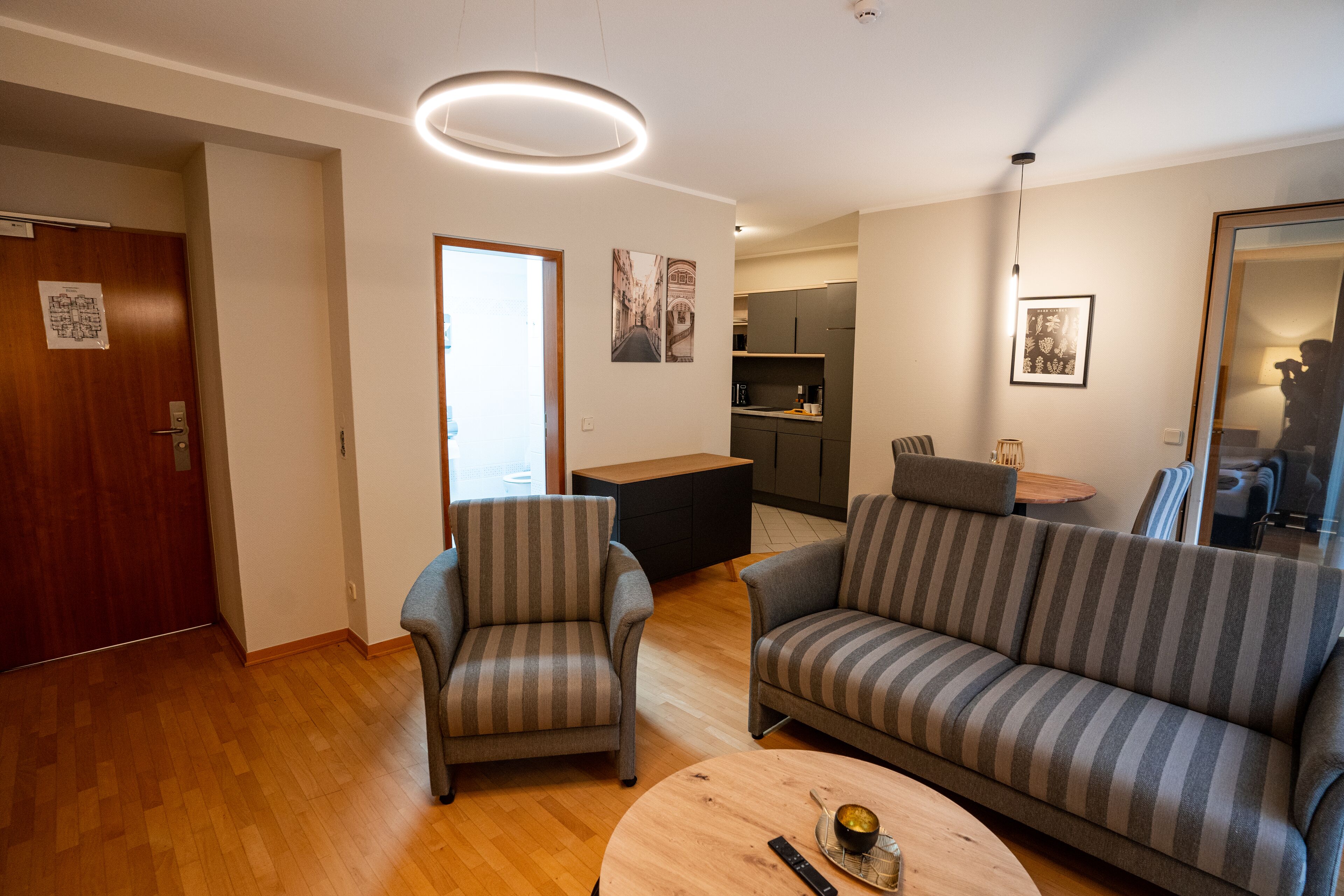 Una sala de estar moderna con un sofá, un sillón y una mesa redonda de centro.
