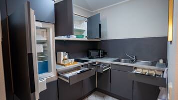 A compact kitchen with a built-in microwave, a sink, and a refrigerator with a partially open door.