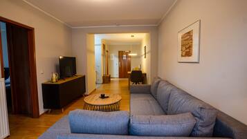 A modern living room with a grey sofa, a wooden coffee table, and a TV on a black stand.
