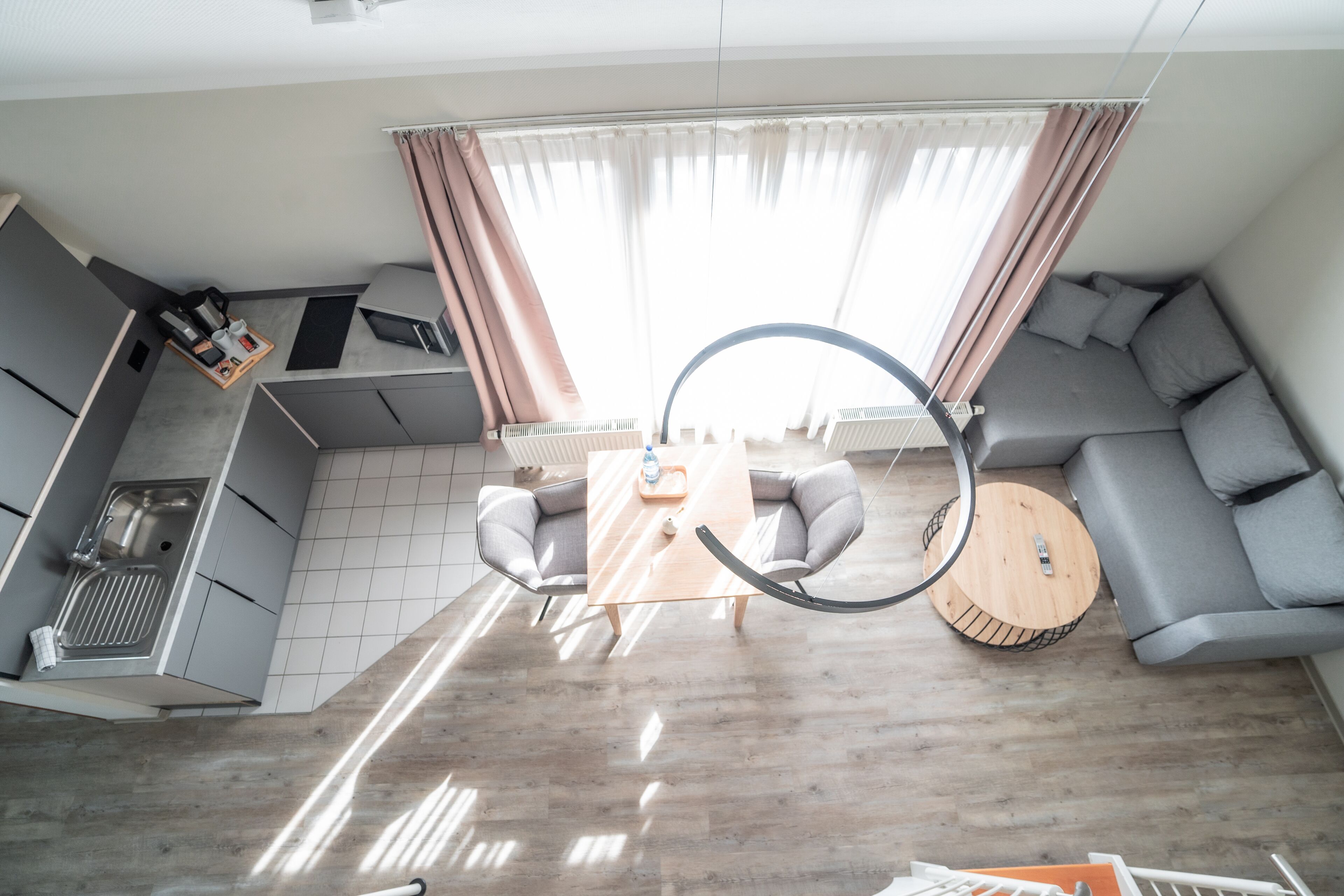 A modern living space with a kitchen, seating area, and a large window with curtains.
