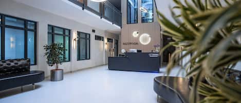 A modern reception area with a reception desk, seating, and a staircase.