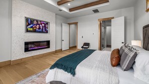 Een moderne slaapkamer met een open haard, een bed met kussens en een televisie aan de muur.