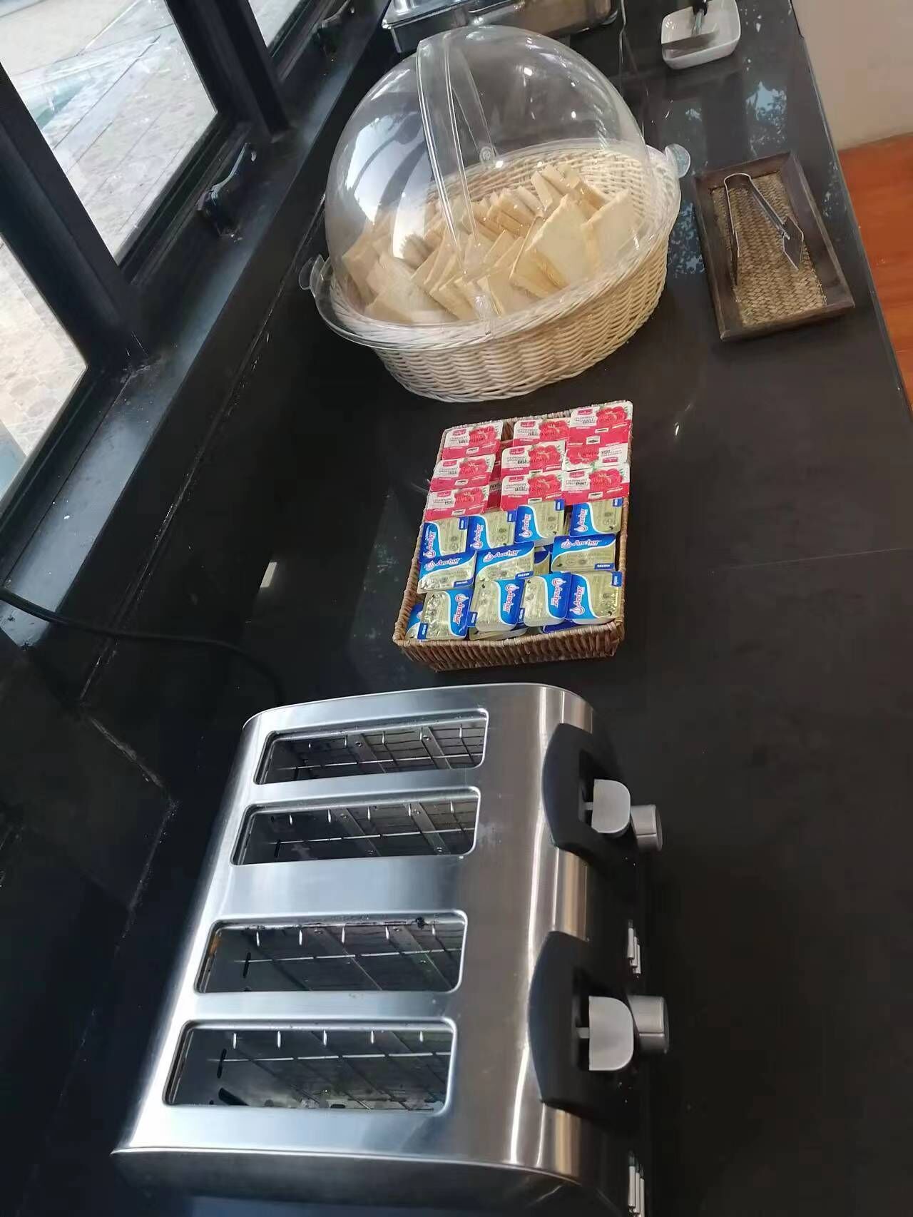 A kitchen area with a toaster, a basket of bread, and a package of butter.