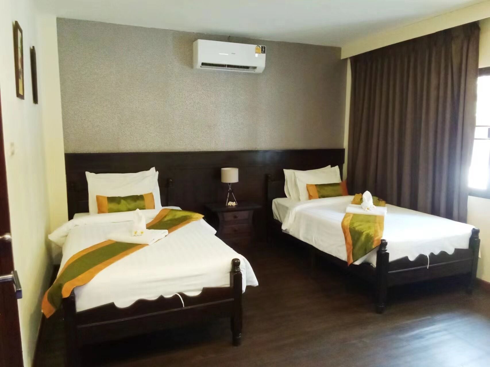 Une chambre d’hôtel avec deux lits, une table de chevet, une lampe et un appareil de climatisation.