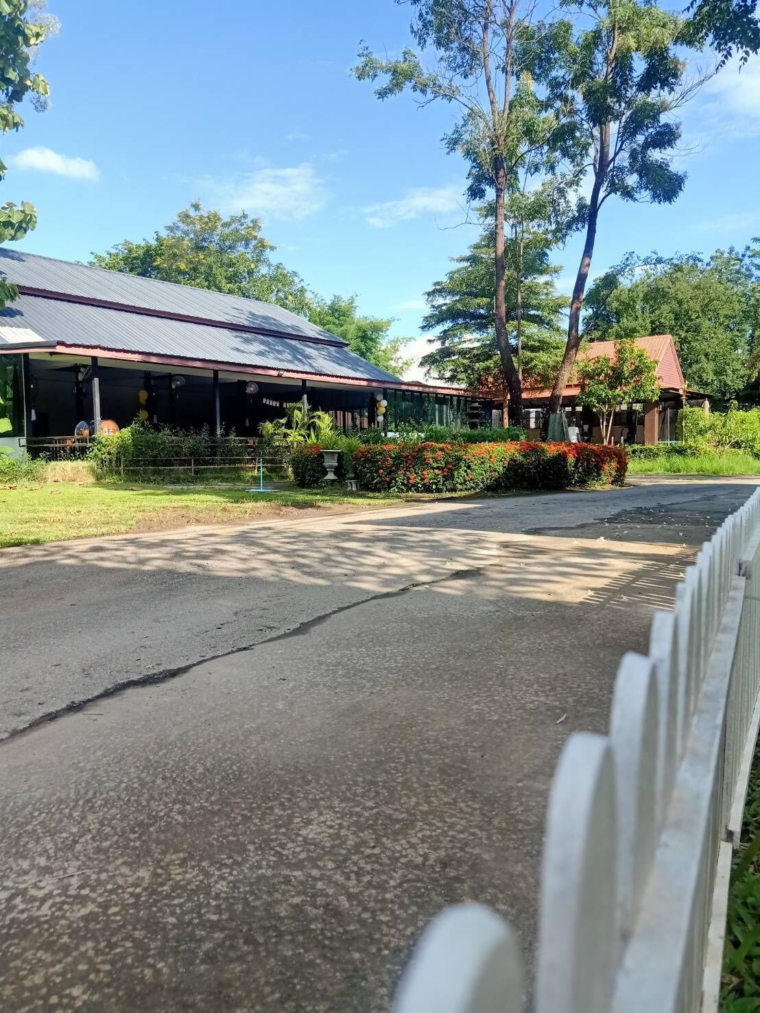 A building with a covered porch, surrounded by greenery and trees.
