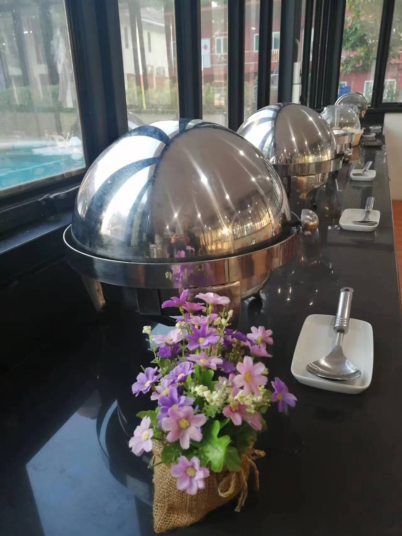 A buffet setup with covered food containers and a small flower arrangement on the counter.