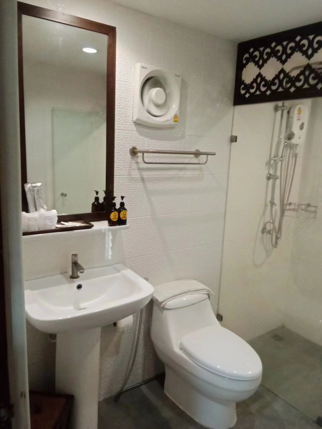 Une salle de bain avec un lavabo blanc, des toilettes et un espace douche.