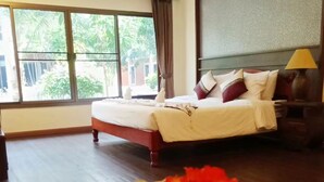 Habitación de hotel con una cama grande, una mesita de noche, una lámpara y vista a zonas verdes por la ventana.