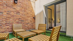 A patio with wooden furniture and a brick wall.