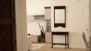 A modern interior with a wooden floor, a console table with a mirror, and a potted plant.