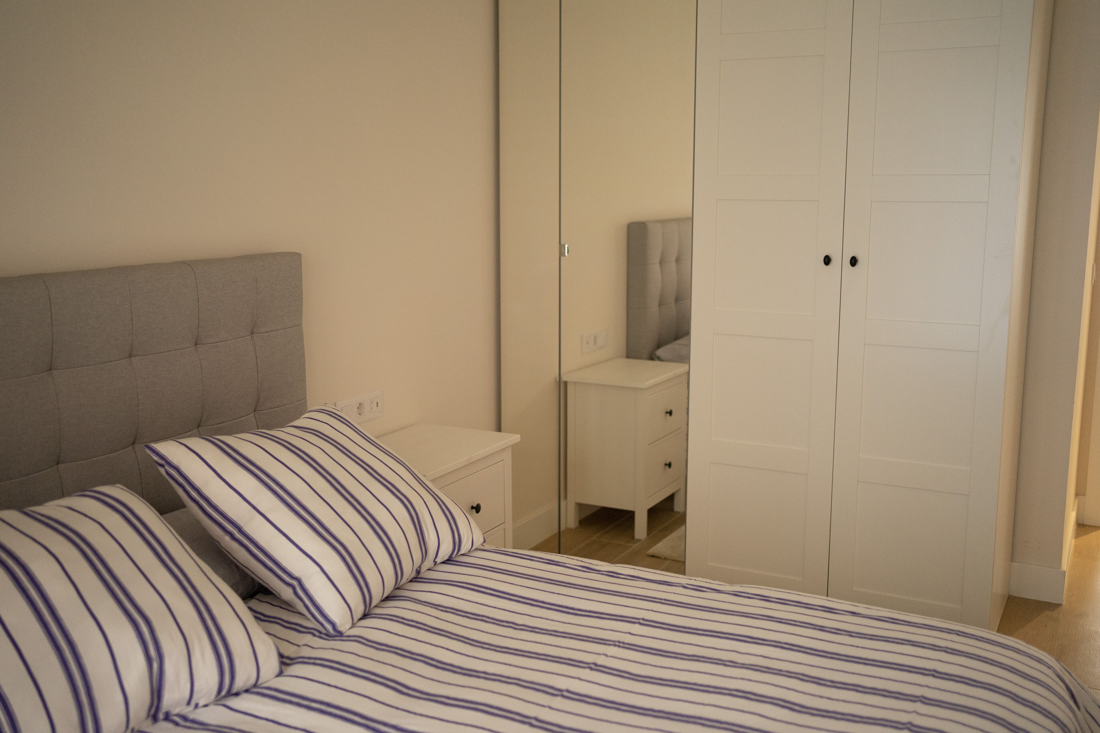 Un dormitorio con cama, mesita de noche, cómoda y armario.