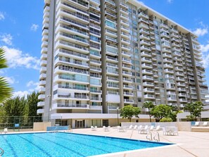 Un hôtel de grande hauteur doté d’une piscine et de chaises longues.