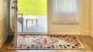 Una habitación con una puerta corrediza de vidrio que da a un patio con vistas a un campo verde y un árbol.