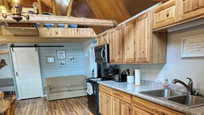 A kitchen with wooden cabinets, a granite countertop, a sink, and a ceiling fan. - Cozy escape in Portage Lake. Sleeps up to ten people!  (Portage Lake)