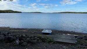 A rocky shoreline with a small boat and a wooden dock. - Cozy escape in Portage Lake. Sleeps up to ten people!  (Portage Lake)