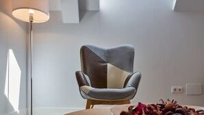 Een moderne kamer met dakraam, een eigentijdse stoel, een vloerlamp en een tafel met gedroogde bloemen.