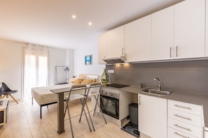 A modern kitchen with a dining area, a sofa, and a view of the outdoors. - Old Town • Studio - Unik Vacation (Tarragona)
